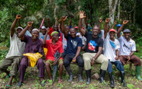 Albert Tucker, Co-Founder of Karma Drinks and Chairman on the Karma Foundation sits with a group of team members. They're all smiling and raising their hands in the air.