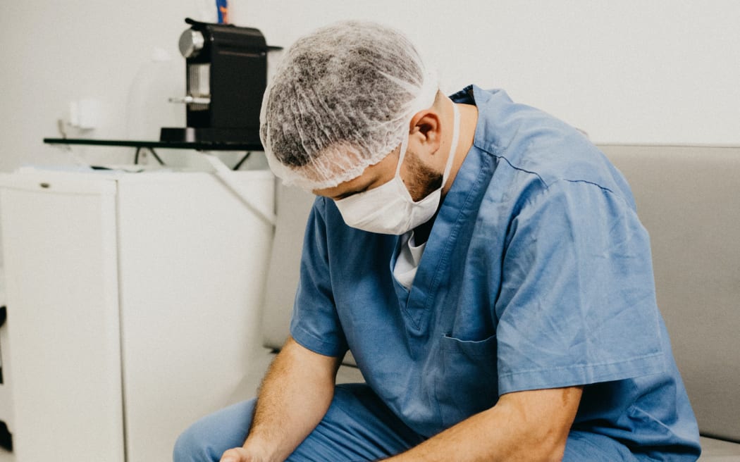 A man in hospital scrubs wit his head down