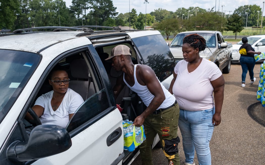 Residents distribute cases of water at Grove Park Community Center in Jackson, Mississippi, on September 3, 2022. - Jackson is enduring days without clean running water, with authorities urging those who still had supplies to shower with their mouths closed. The city, where 80 percent of the population is Black and poverty is rife, has been experiencing recurring water crises for years. But this week's ordeal plunged Jackson into an emergency, with days of major flooding disrupting the operation of a critical but aging water treatment plant. (Photo by SETH HERALD / AFP)