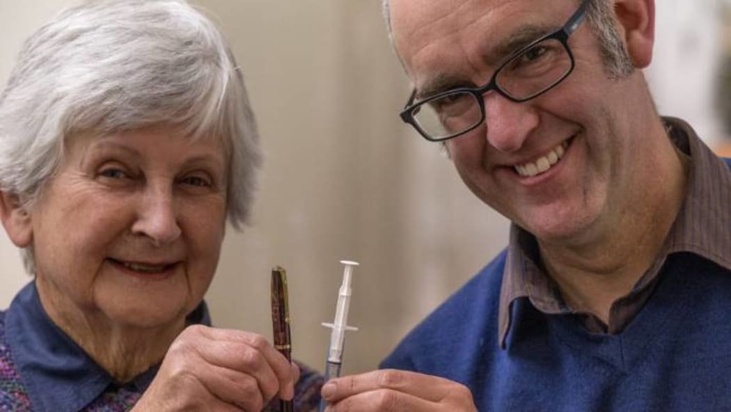 Marilyn Murdoch and Chris Rapley from South Canterbury Museum hold Colin Murdoch's fountain pen and prototype disposable plastic syringe.