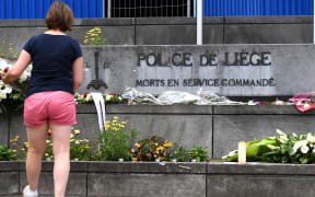 A woman puts flowers in front of Liege police headquarters in tribute to the victims of a shooting in Liege on May 30, 2018.