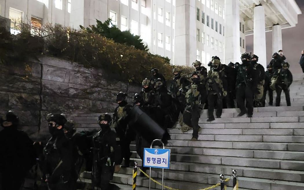 Soldiers withdraw from the National Assembly in Seoul on December 4, 2024, after the passage of a resolution during an emergency plenary session urging South Korea President Yoon Suk Yeol to revoke martial law. - Yoon on December 3 declared martial law, accusing the opposition of being "anti-state forces" and saying he was acting to protect the country from "threats" posed by the North. (Photo by YONHAP / AFP) / - South Korea OUT / NO USE AFTER DECEMBER 12, 2024 17:00:00 GMT -  - SOUTH KOREA OUT / NO ARCHIVES -  RESTRICTED TO SUBSCRIPTION USE