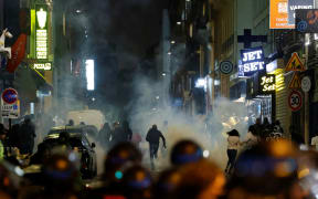Demonstrators run as French police officers use tear gas in Paris on 2 July, 2023, five days after a 17-year-old man was killed by police in Nanterre, a western suburb of Paris.