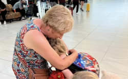 Helen Ellis gives one of her grandchildren a big hug at the airport.