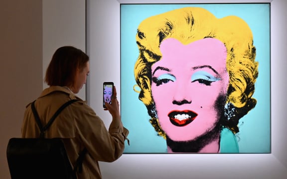 A woman takes a photo of Andy Warhol's 'Shot Sage Blue Marilyn' during Christie's 20th and 21st Century Art press preview at Christie's New York on April 29, 2022 in New York City.