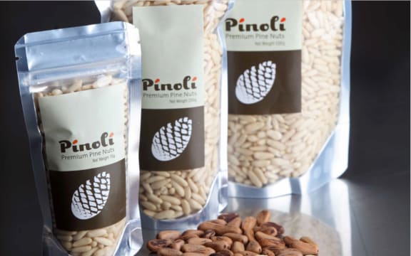 A shot of three packets of Pinoli Premium Pine Nuts, with loose nuts in the foreground.