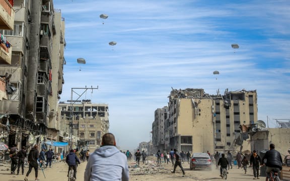 Palestinians run along a street as humanitarian aid is airdropped in Gaza City on March 1, 2024, amid the ongoing conflict between Israel and the Hamas militant group. For months, aid workers have warned of an increasingly desperate situation for Gazan civilians, and on February 26 an official from the UN humanitarian office OCHA said widespread starvation was "almost inevitable". (Photo by AFP)
