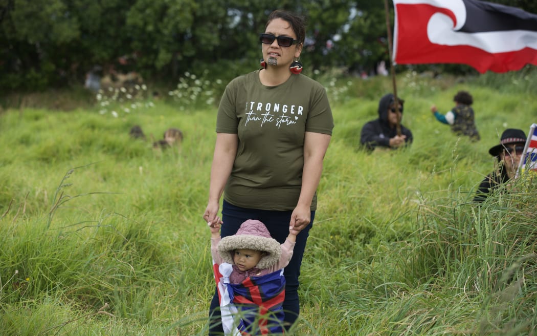 Māmā and pēpi play in the long grass at Ihumātao.