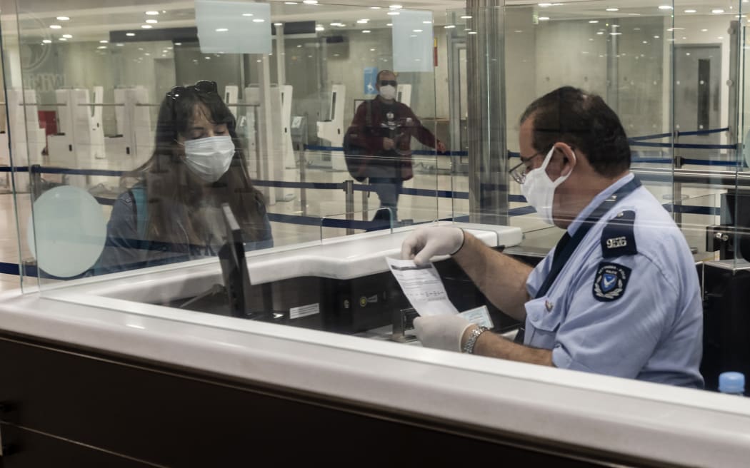 A passenger wearing a mask waits with her documents at passport control at Larnaca International Airport, 9 June  2020.