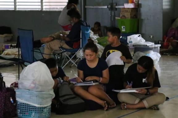 Young students do school work to pass the time while seeking shelter Monday at Astumbo Elementary School.