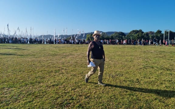 A group of 200 or so people hold up white flags as Tame Iti arrives at Te Whare Runanga on Waitangi Day 2024.