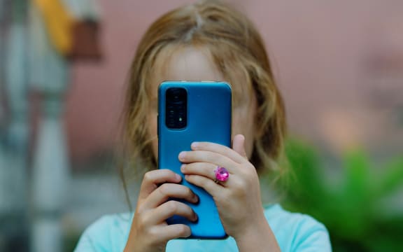 Girl holds up phone to her face.