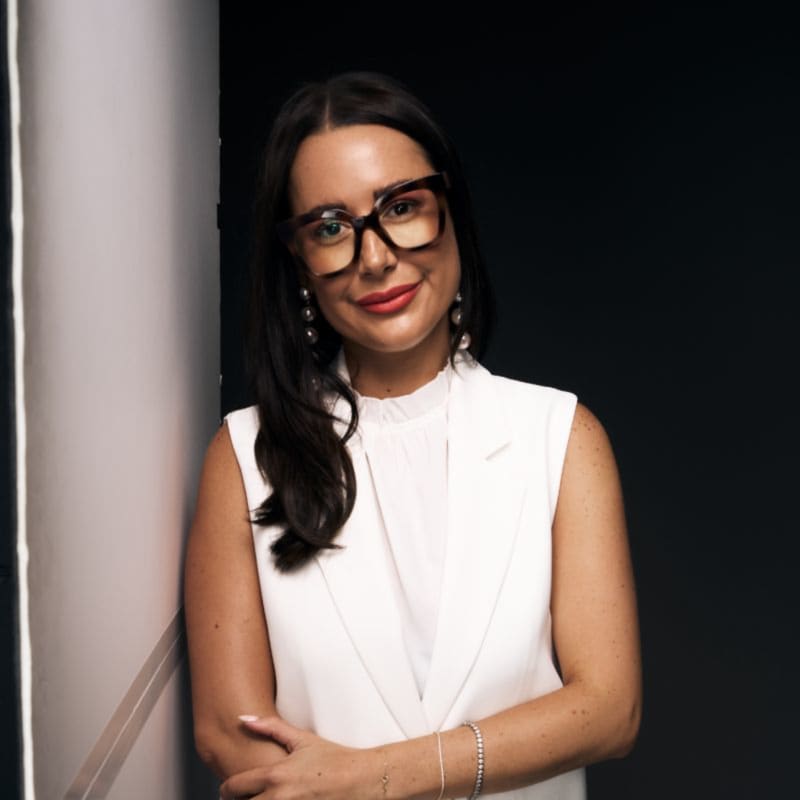 Gabriella Pomare is a dark-haired woman with dark-rimmer glasses and a white sleeveless top.