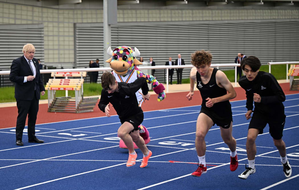 Britain's Prime Minister Boris Johnson (L) sets off a race between the Commonwealth Games Mascot, Perry The Bull and athletes from Burchfield Harriers on the training track beside Alexander Stadium in Birmingham, central England, on May 12, 2022. (Photo by Oli SCARFF / POOL / AFP)