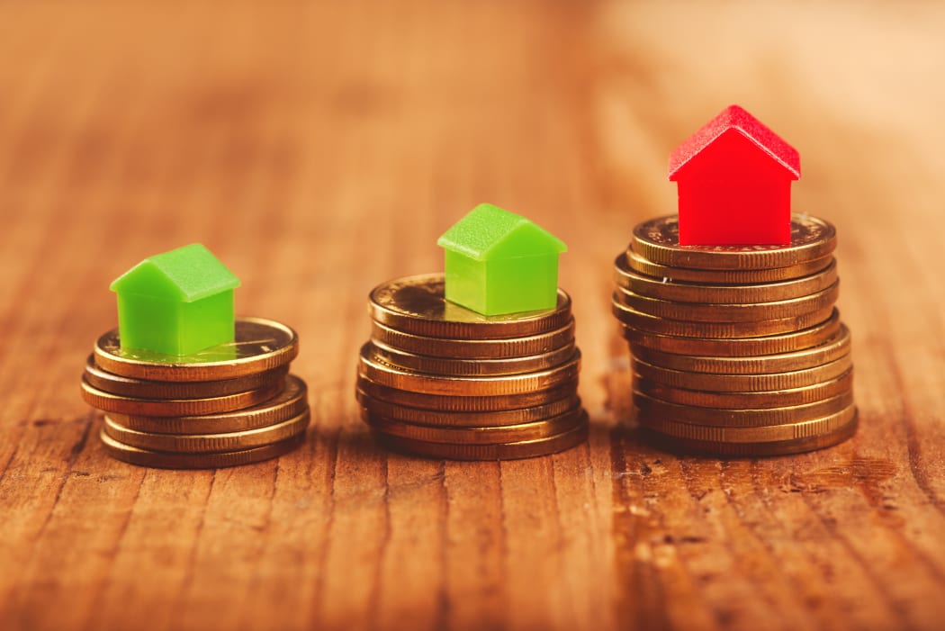 Real estate mortgages, as illustrated by houses stacked on top of coins.