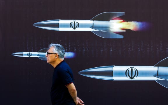 A man walks past a banner depicting missiles along a street in Tehran on April 19, 2024. Iran's state media reported explosions in the central province of Isfahan on April 19, as US media quoted officials saying Israel had carried out retaliatory strikes on its arch-rival. (Photo by AFP)