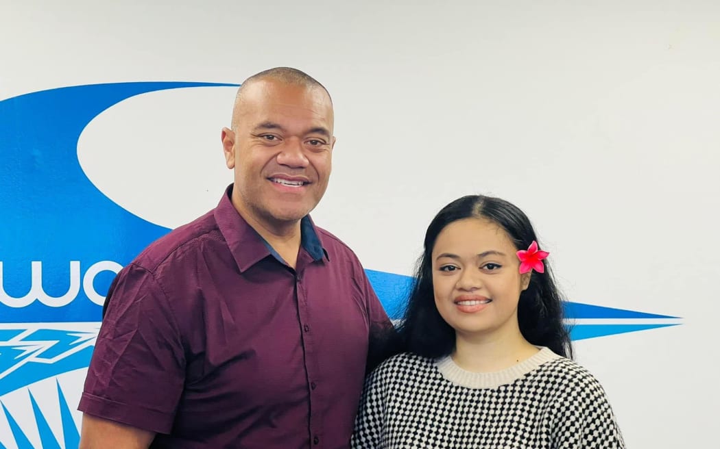 Efeso and Hana stand side by side, smiling at the camera.