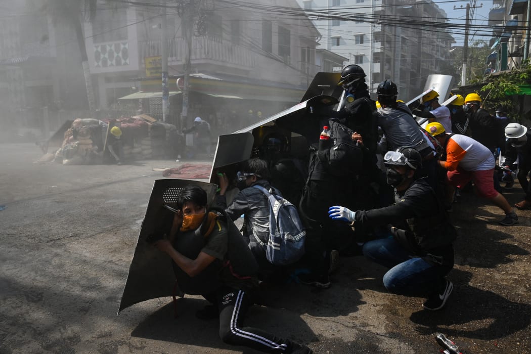Protesters take shelter behind homemade shields after tear gas was fired during a demonstration against the military coup in Yangon.