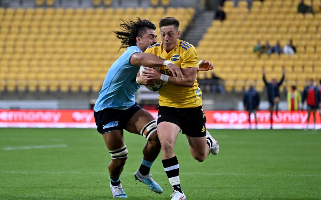 Cameron Roigard of the Hurricanes is tackled by Charlie Gamble of the Waratahs
