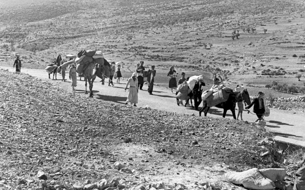 FILE - A group of Palestinian refugees walk along the dusty road from Jerusalem to Lebanon, carrying their children and belongings with them, on Nov. 9, 1948. (AP Photo/Jim Pringle, File)