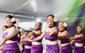 Performers dancing and smiling at the Pasifika Festival.