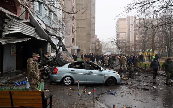 Military and onlookers stand at the site where a helicopter crashed near a kindergarten outside the capital Kyiv, killing Sixteen people, including two children and Ukrainian interior minister, on January 18, 2023, amid the Russian invasion of Ukraine. (Photo by Sergei Supinsky / AFP)
