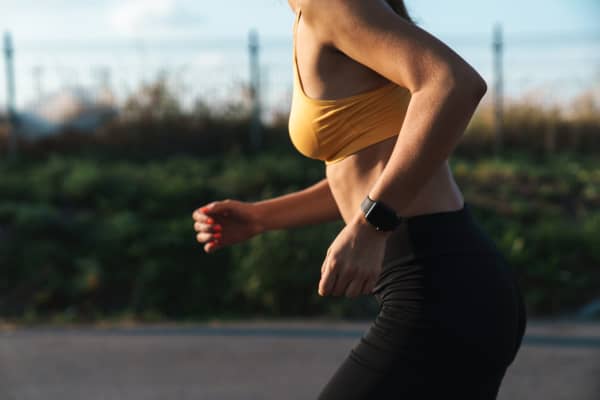 Cropped image closeup of slim woman in sportswear running while doing workout outdoors