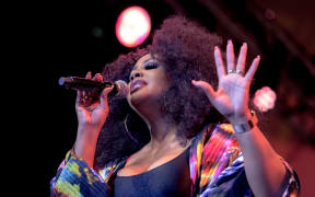 US singer Lalah Hathaway holds a microphone, closes her eyes and sings into it