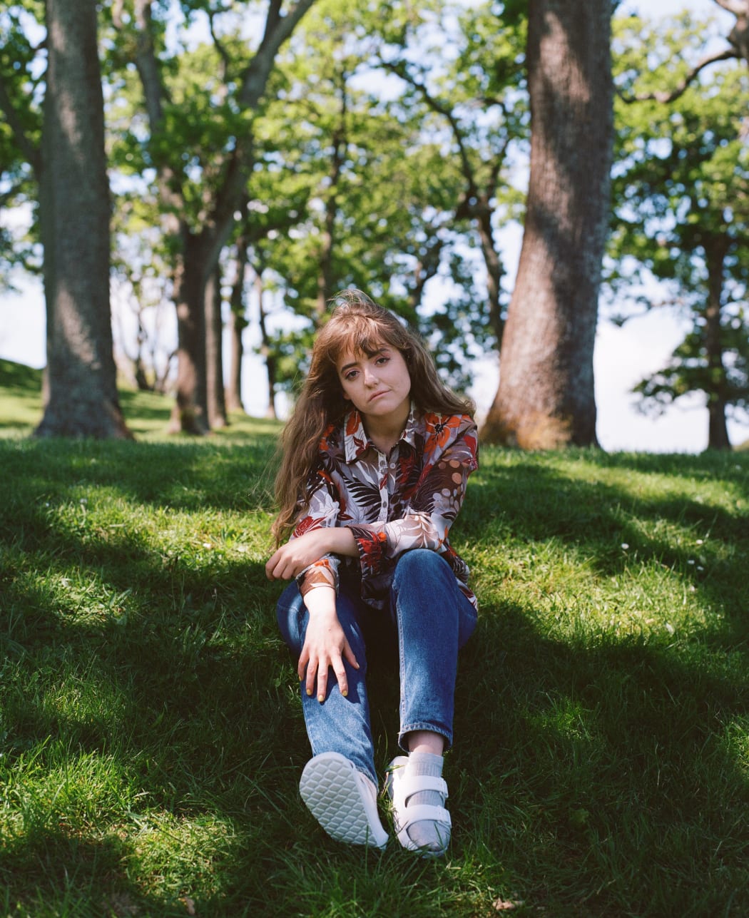 Young woman sitting on grass in a grove of trees