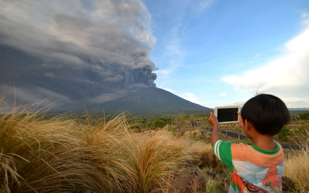 A boy takes pictures during Mount Agung's eruption.