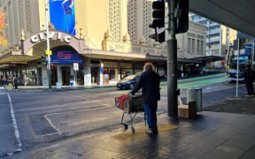 A homeless man waits to cross the road on Auckland's Queen Street.