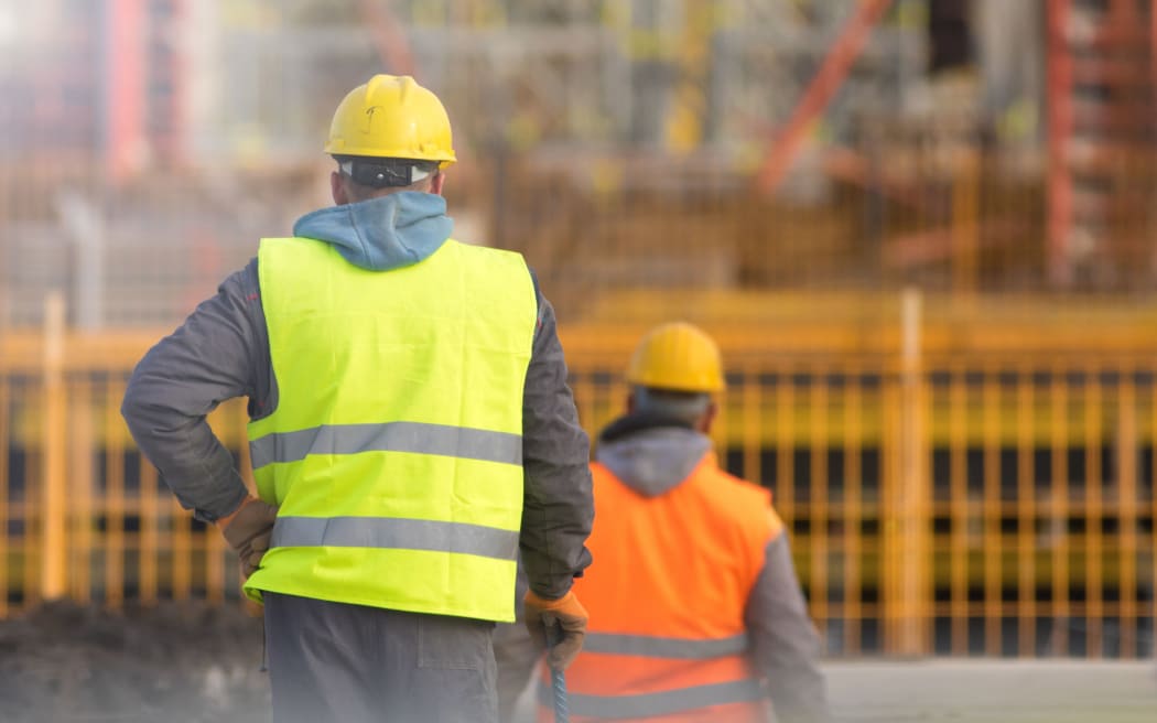 Two builders in yellow and orange at the construction site