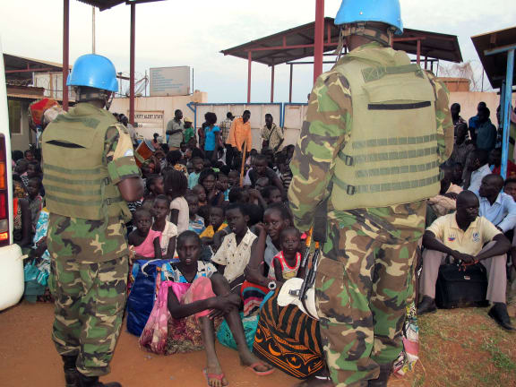 Soldiers stand guard as people seek shelter in a compound near Juba airport on Wednesday.
