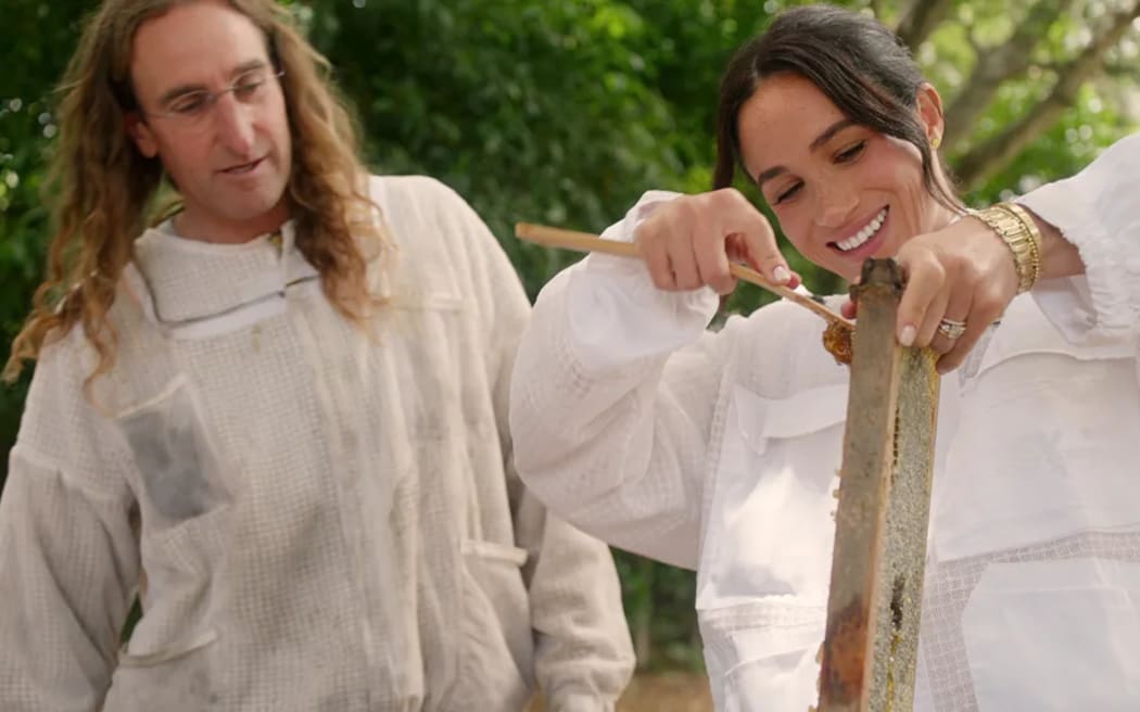 Meghan pictured scraping honey off hive frames with beekeeper Branden Aroyan.