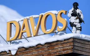 A Swiss police sniper stands guard on the roof next to the Congress centre during the first day of the WEF.