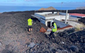 GNS scientists at a building that has been engulfed in lava.