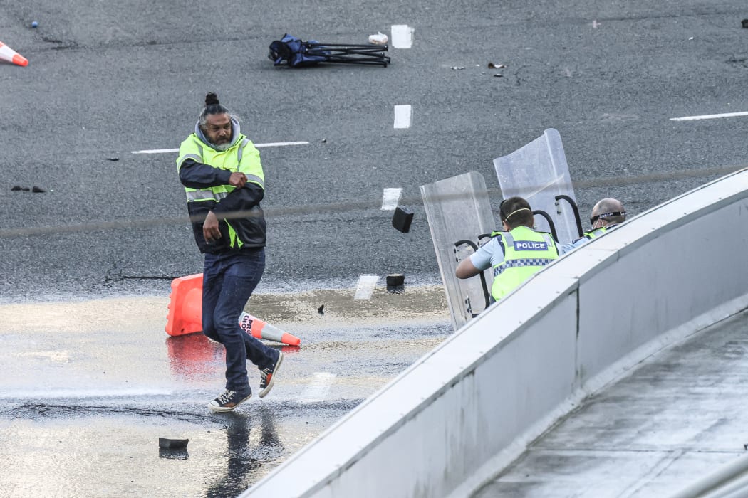 A man throws a paving stone at police at close range
