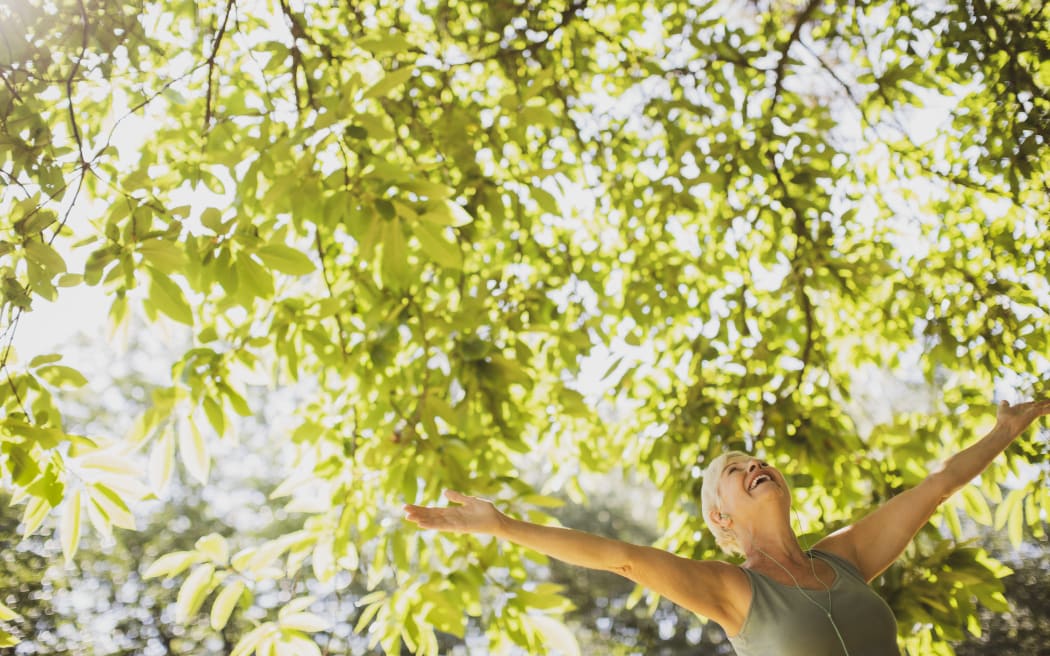 Exuberant senior woman with arms outstretched under sunny tree. (Photo by CAIA IMAGE/SCIENCE PHOTO LIBRARY / NEW / Science Photo Library via AFP)