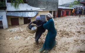 People walking through a flooded street in Pétion ville, Haiti, on 23 August during the passage of  Tropical Storm Laura. Heavy rains hammered Haiti, killing at least five people.