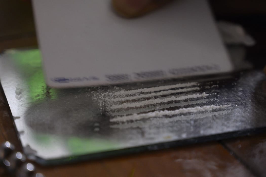 Someone prepares several lines of cocaine on a mirror.