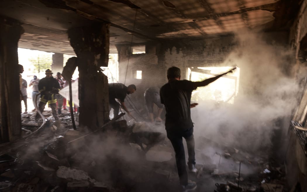 People and rescue workers assess the damage inflicted on a house during an Israeli raid in the occupied West Bank city of Jenin on 5 July, 2024.  (Photo by Jaafar ASHTIYEH / AFP)