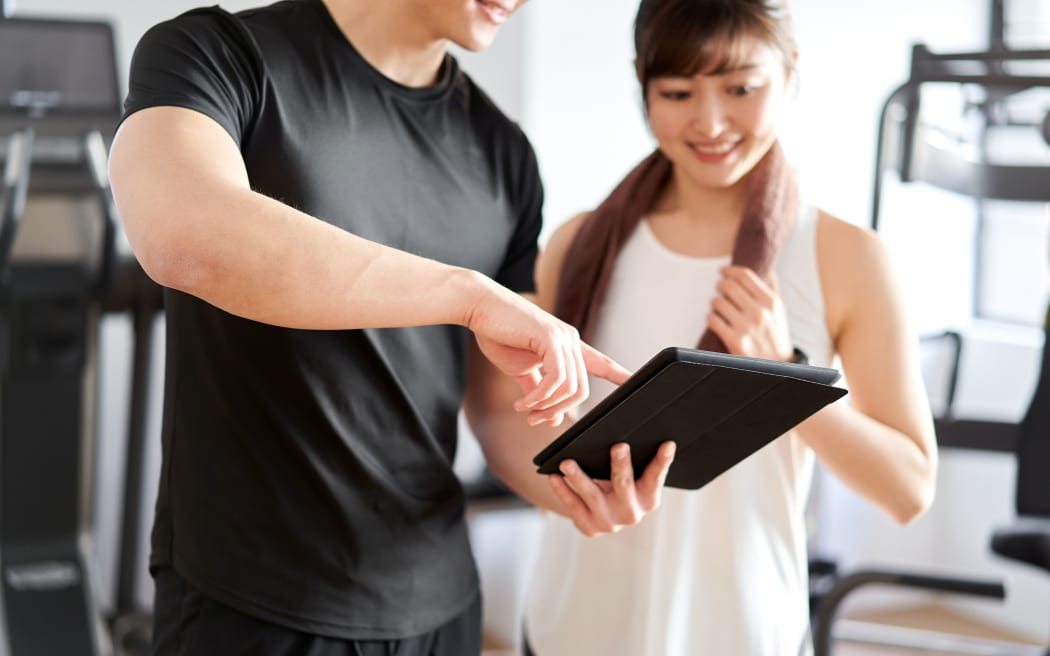 Asian male personal trainer teaching using tablet