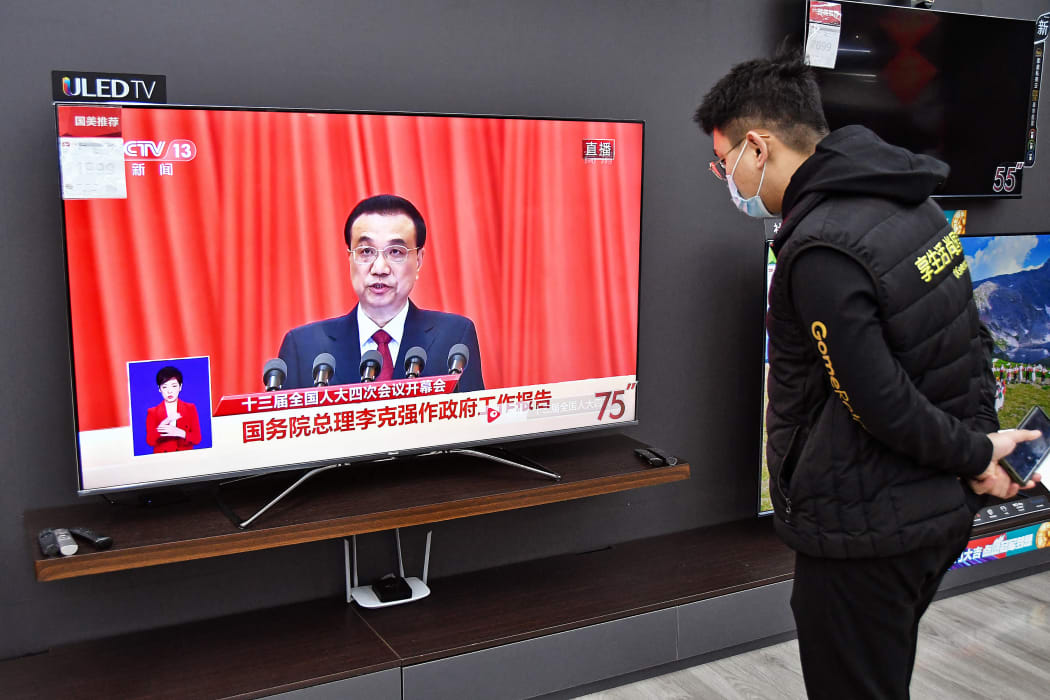 A man watches a live broadcast from Beijing of China's Premier Li Keqiang delivering a speech during the opening session of National People's Congress on March 5, 2021.
