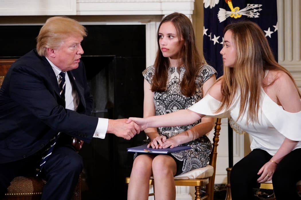 US President Donald Trump shakes hands with Marjory Stoneman Douglas High School student Ariana Klein watched by fellow student Carson Abt