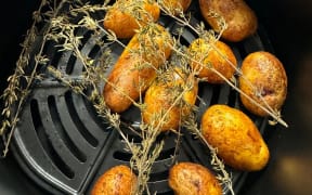 Skin on roast potatoes sitting in an air fryer.