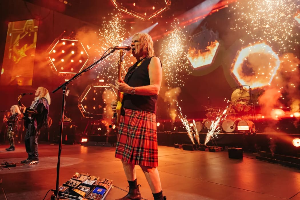 Still from Spinal Tap II: The End Continues showing Nigel Tufnell (Christopher Guest) on stage wearing a kilt.