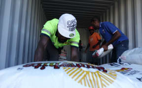 NDMO volunteers stack bags of rice in shipping containers for safe-keeping pending the results of the unfortunately named Rapid Assessments.