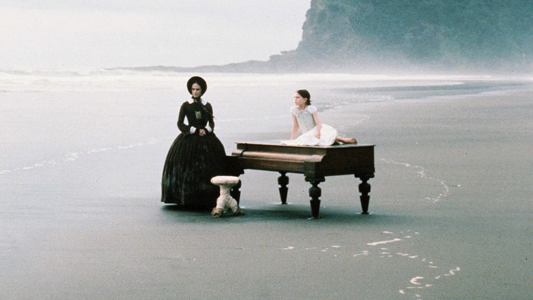 Screen shot from The Piano (with actors and piano on the beach)