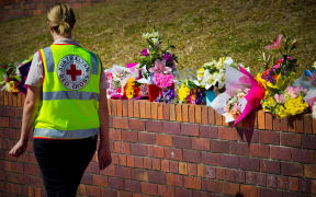 A Member of the Australian Red Cross counselling team walks past a makeshift floral tribute at the Dreamworld theme park on the Gold Coast.