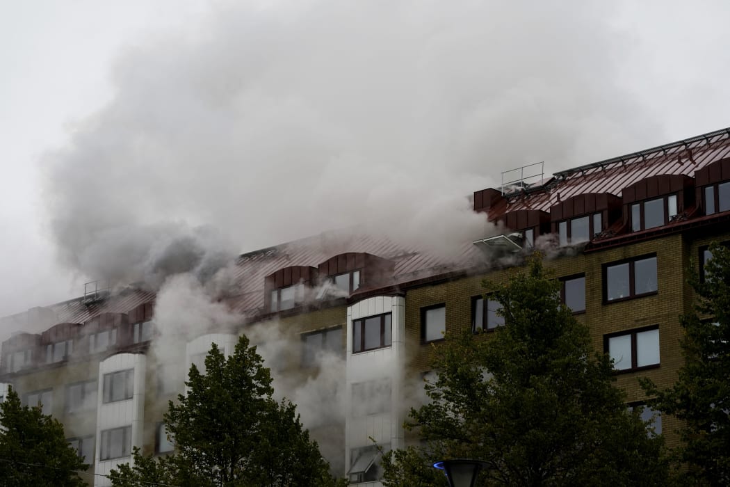 Smoke billows from a building as firefighters battle a blaze at the site of an explosion in central Gothenburg.